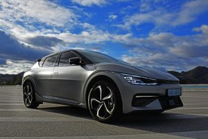 A sleek electric Kia EV6 parked outdoors against a stunning sky and landscape.